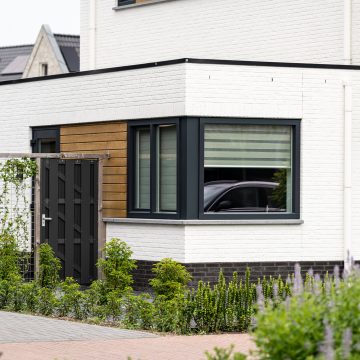 Strak donker hoekkozijn in contrast met houtafwerking.